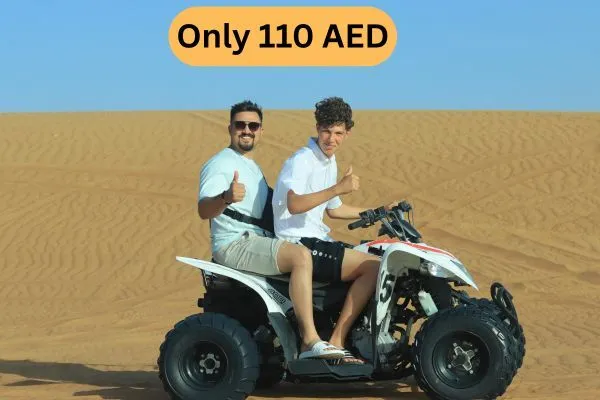 Two Tourists Enjoying ATV Quad Bike Ride on Sand Dunes in Desert Safari Abu Dhabi