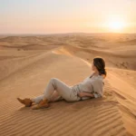 Woman relaxing on golden sand dunes during Abu Dhabi desert safari at sunset