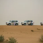 Desert safari jeep tour with 4x4 vehicles parked on Abu Dhabi sand dunes