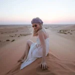 Guest enjoying the sunset during an Evening Desert Safari Abu Dhabi on the golden sand dunes.