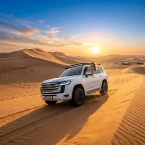 Luxury Morning Desert Safari Abu Dhabi at sunrise with a 4x4 Land Cruiser driving across golden sand dunes.