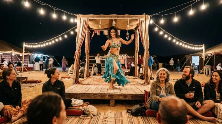 A belly dancer performing on the small stage while guests watch from cushions at an Abu Dhabi desert camp