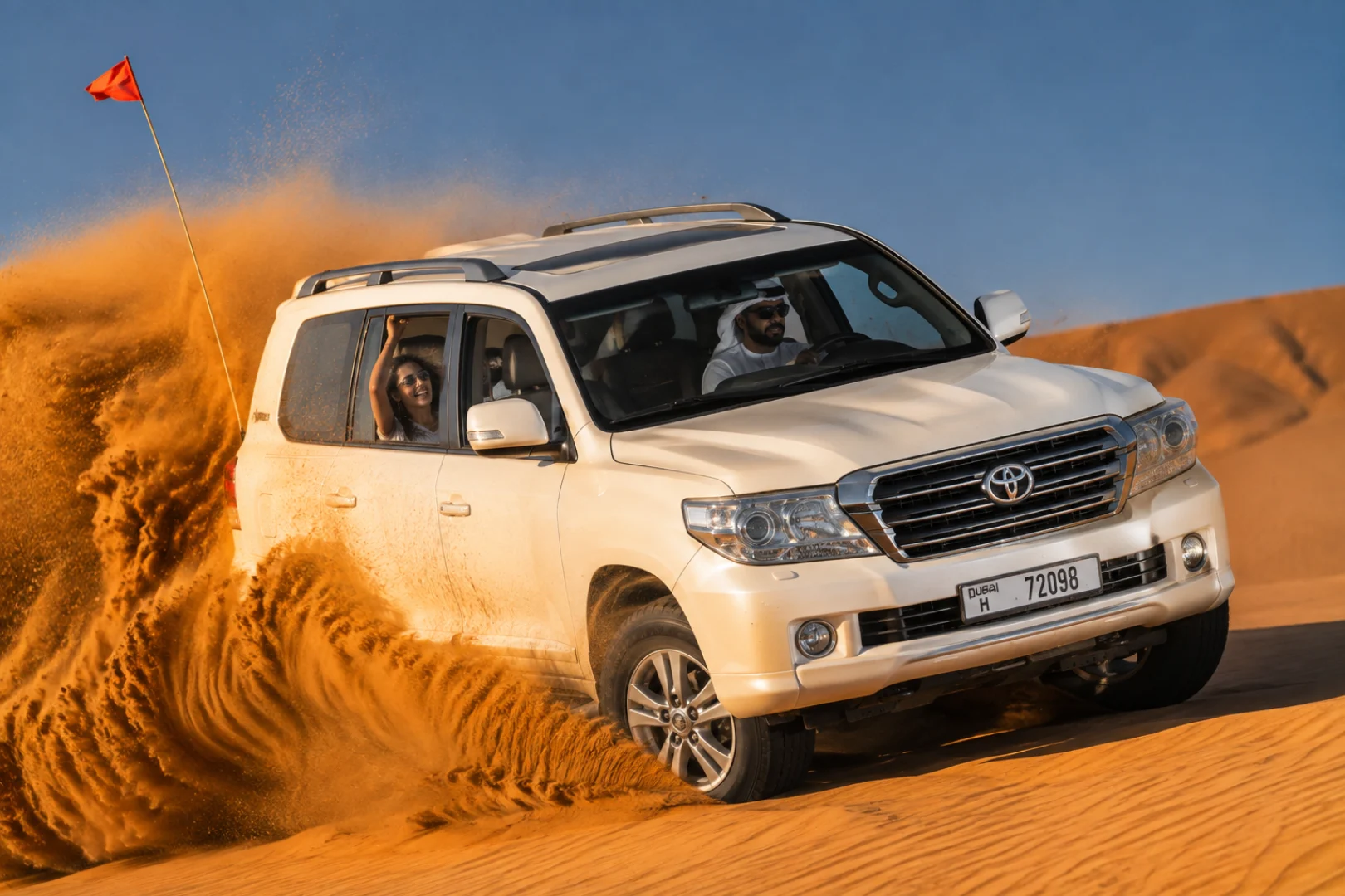 White 4x4 Land Cruiser dune bashing across golden sand dunes on an Abu Dhabi desert safari