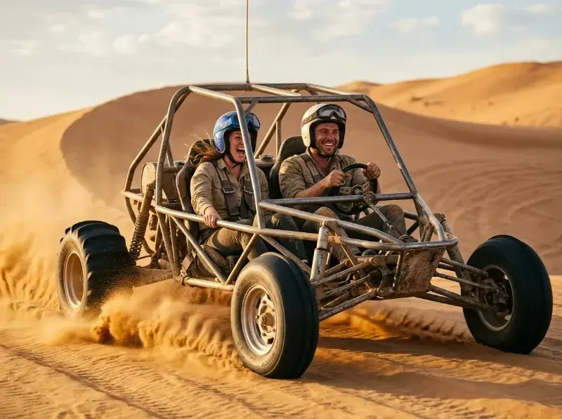 Two guests driving a two-seater dune buggy across the sand dunes on a dune buggy tour in Abu Dhabi