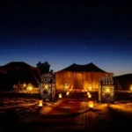 Traditional desert camp illuminated by lanterns during an Overnight Desert Safari Abu Dhabi.